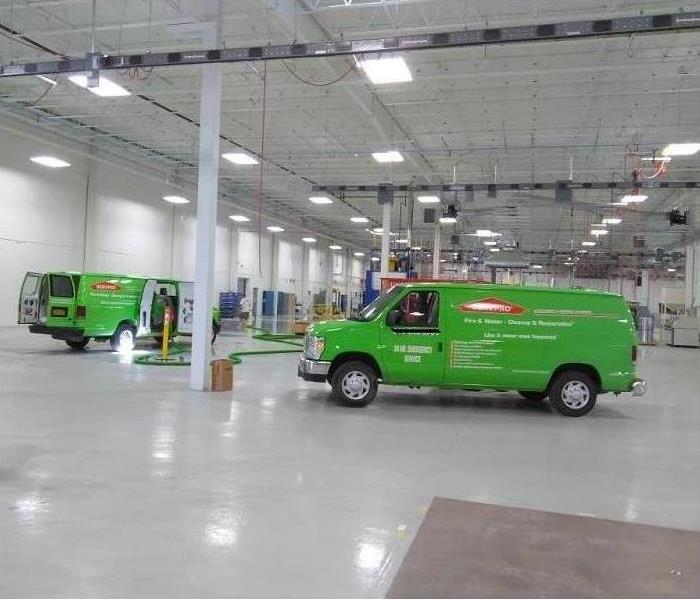 2 SERVPRO Green vans parked inside a gleaming white commercial warehouse facility