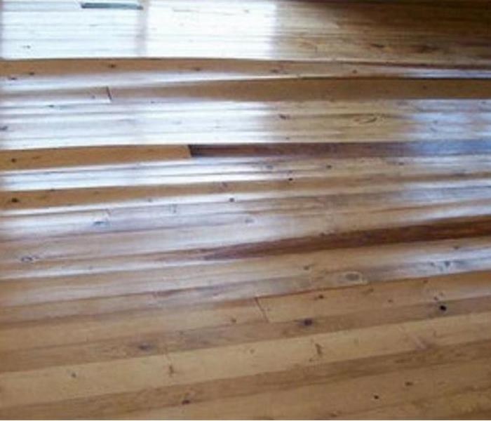A hardwood floor that has buckled and cupped due to water damage underneath.