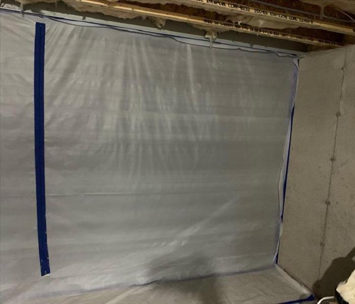 A dried out basement with plastic containment sheets up to prevent further damage