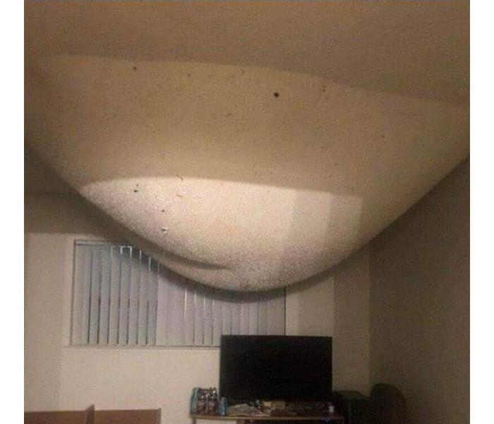 A giant paint bubble on the ceiling of a room filled with water from a pipe break above.