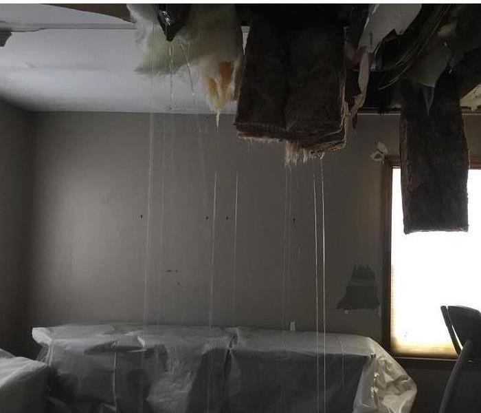 Water pouring out of the insulation and sheet rock inside a bedroom