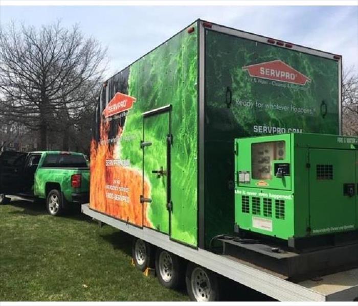 A large Dessicant Dehumidifier wrapped in SERVPRO green and orange, sits on a trailer towed behind a truck.