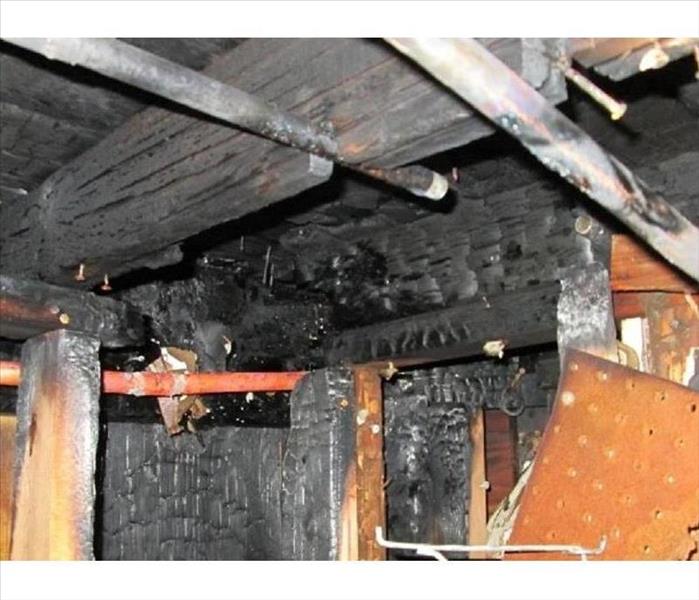 A photo of a basement with burned wooden beams and scorched and charred walls.