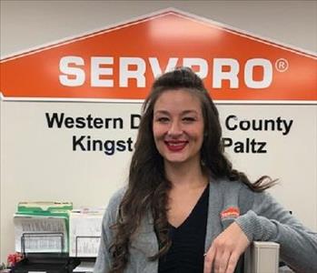 A photo of a smiling female SERVPRO employee with long brown hair in a gray SERVPRO sweater